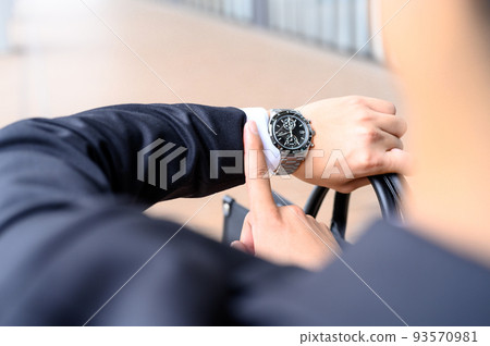 Businessman looking at his watch to check the time 93570981