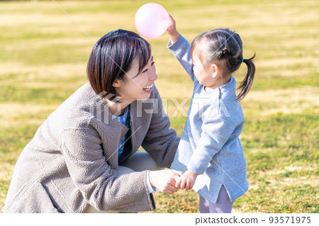 Kindergarteners and nursery teachers playing on the lawn square in the park 93571975