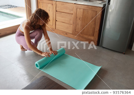 Exercise At Home. Woman Rolling Yoga Mat After Practicing Exercise At Home. Woman Rolling Yoga Mat After Practicing 93576364
