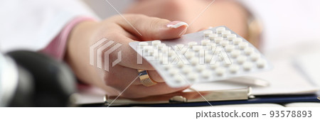 Doctor hand holding package of pills in workplace closeup 93578893
