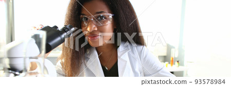 Black woman scientist in goggles, conducts study using microscope Black woman scientist in goggles, conducts study using microscope 93578984
