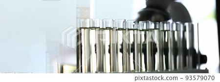 Glass test tubes with yellow liquid on of microscope 93579070