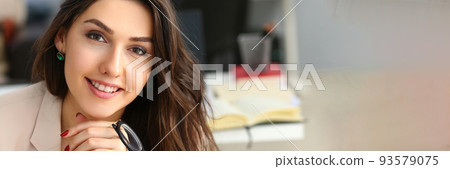 Smiling confident businesswoman at workplace looks up Smiling confident businesswoman at workplace looks up 93579075