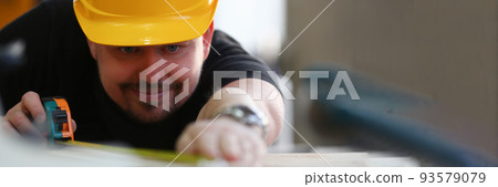 Man builder in helmet makes measurements with tape measure Man builder in helmet makes measurements with tape measure 93579079
