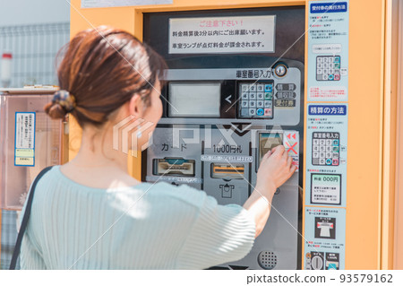 A woman who puts money in a coin parking lot 93579162