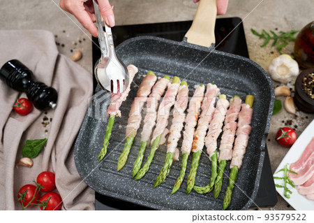 Healthy food - Asparagus wrapped with bacon and spices on grill pan Healthy food - Asparagus wrapped with bacon and spices on grill pan 93579522