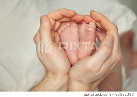 Newborn baby feet in dad's hands 93582396