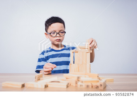Asian boy playing with a wooden puzzle Asian boy playing with a wooden puzzle 93582874
