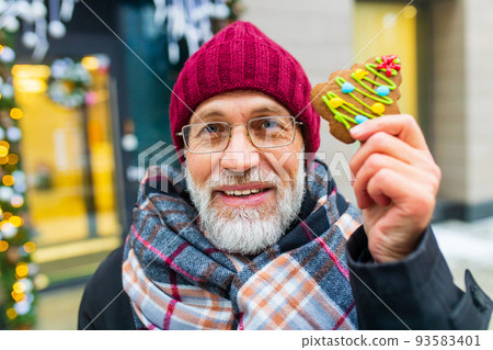 happy man showing green sweet cookie christmas tree shape outdoors in winter market 93583401