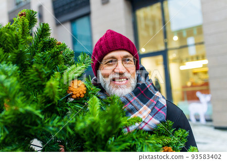 happy retired man walking by street with christmas tree to home from market 93583402