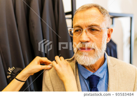 mature tailor working with sewing pattern in atelier 93583484