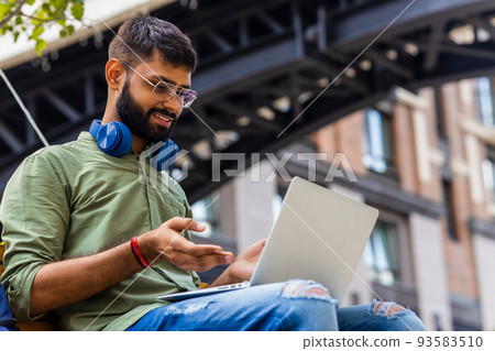 Portrait Indian student programmer using laptop computer in park Portrait Indian student programmer using laptop computer in park 93583510