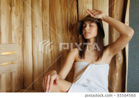 Beautiful woman in white towel relaxing in sauna 93584568