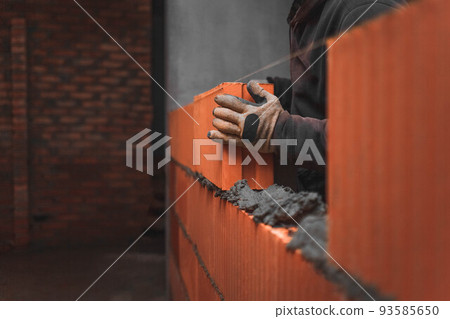 Builder laying a large brick block on the mortar creating a wall. Builder laying a large brick block on the mortar creating a wall. 93585650