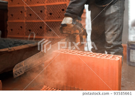 Construction worker cuts a brick with a saw Construction worker cuts a brick with a saw 93585661