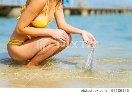 woman picking up a plastic trash from water in tropical island 93586326