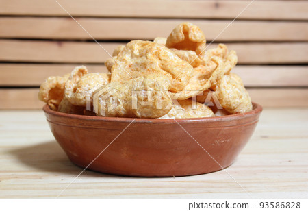 Bowl of Fried Pork Skins on Wooden Table in Rustic Kitchen Bowl of Fried Pork Skins on Wooden Table in Rustic Kitchen 93586828