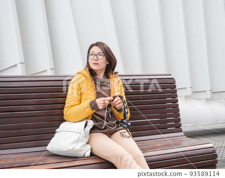 Woman is crocheting outdoor. Tranquil leisure of female in urban park. Anti-stress hobby. Woman is crocheting outdoor. Tranquil leisure of female in urban park. Anti-stress hobby. 93589114