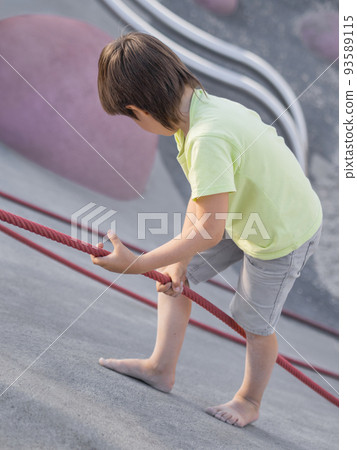 Boy climbes up a concrete slope of modern children's sports and playground. Kid overcomes fear and learn new things. Active leisure outdoors. Sporty lifestyle. Boy climbes up a concrete slope of modern children's sports and playground. Kid overcomes fear and learn new things. Active leisure outdoors. Sporty lifestyle. 93589115