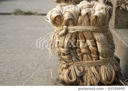 A thick brown  bundle of  raw jute has on the ground     93589990