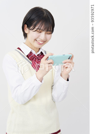 一個高中女生在白色背景上微笑著看著智能手機 93592971