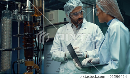 Two scientist in professional uniform working in laboratory Two scientist in professional uniform working in laboratory 93596434