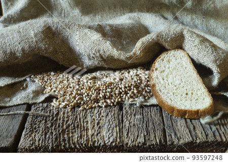 Wheat grain with a bag on a wooden table Wheat grain with a bag on a wooden table 93597248