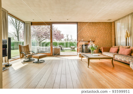 Interior of modern room illuminated with sunlight from ceiling window and door in modern house Interior of modern room illuminated with sunlight from ceiling window and door in modern house 93599951