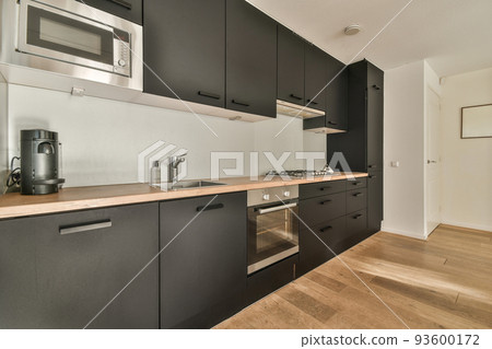 Interior of minimalist style kitchen with simple cupboards and modern appliances in light apartment 93600172