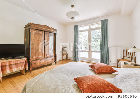 Home interior design of bedroom with bed and wooden wardrobe placed in corner near window in modern apartment 93600680