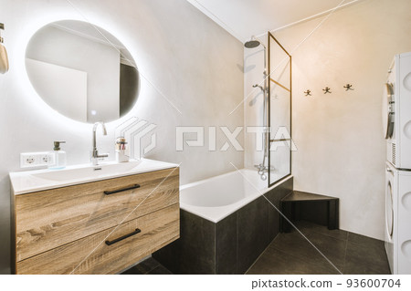 Sinks with mirrors and clean bathtub located near shower box with glass door in modern bathroom with white tiled walls 93600704