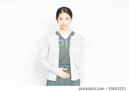 A woman standing in front of a white background and putting her hand on her stomach 93601015
