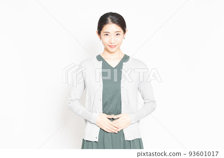 A woman standing in front of a white background and putting her hand on her stomach 93601017