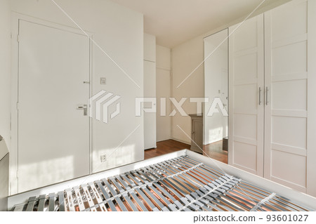 Home interior design of bedroom with bed and wooden wardrobe placed in corner near window in modern apartment 93601027
