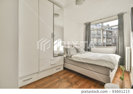 Modern home interior design of small mansard bedroom with white walls and soft cozy bed and minimalist style shelves in daylight with illumination 93601215