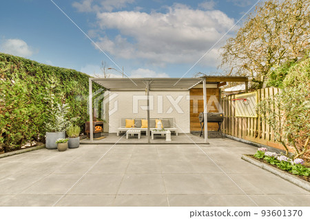 Neat paved patio with sitting area and small garden near wooden fence 93601370