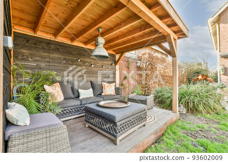 Neat paved patio with sitting area and small garden near wooden fence 93602009