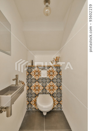 Modern flush toilet and ceramic sink installed on white tiled walls near mirror and towel in small restroom at home Modern flush toilet and ceramic sink installed on white tiled walls near mirror and towel in small restroom at home 93602159