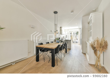 Shabby wooden table with chairs and vase located near comfortable couch against light walls with decorations and TV in modern apartment 93602160