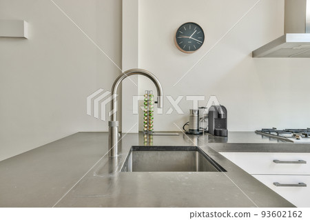 Sink with shiny tap installed under modern counter near jar with spices and gas stove in kitchen at home Sink with shiny tap installed under modern counter near jar with spices and gas stove in kitchen at home 93602162