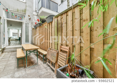 Neat paved patio with sitting area and small garden near wooden fence Neat paved patio with sitting area and small garden near wooden fence 93602521