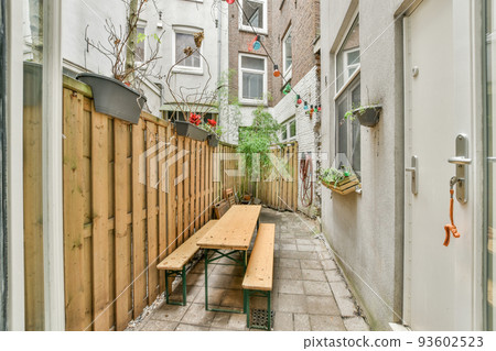 Neat paved patio with sitting area and small garden near wooden fence Neat paved patio with sitting area and small garden near wooden fence 93602523
