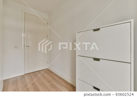 Modern cupboard and vintage chest placed near doors and wicker basket in spacious room with white walls and wooden floor Modern cupboard and vintage chest placed near doors and wicker basket in spacious room with white walls and wooden floor 93602524