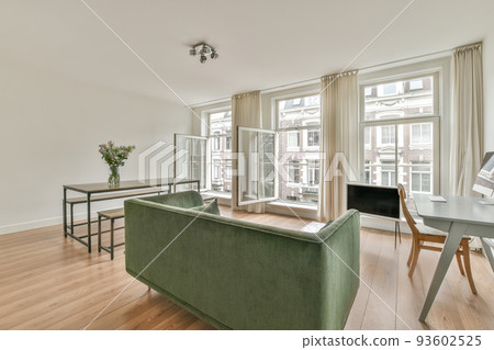 Stylish interior design of living room with light furniture and soft comfy couch and carpet and with pc on cabinet in modern apartment with open kitchen and white walls Stylish interior design of living room with light furniture and soft comfy couch and carpet and with pc on cabinet in modern apartment with open kitchen and white walls 93602525