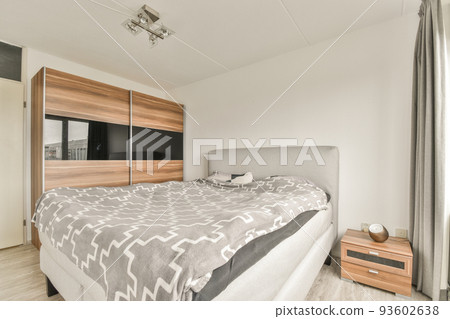 Home interior design of bedroom with bed and wooden wardrobe placed in corner near window in modern apartment Home interior design of bedroom with bed and wooden wardrobe placed in corner near window in modern apartment 93602638