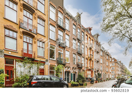 Panorama view of brick houses from an empty sidewalk street with cars, trees and lanterns 93602819