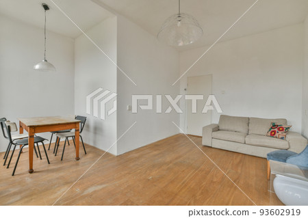 Shabby wooden table with chairs and vase located near comfortable couch against light walls with decorations in modern apartment Shabby wooden table with chairs and vase located near comfortable couch against light walls with decorations in modern apartment 93602919