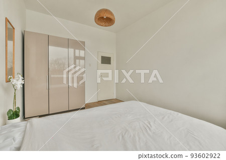 Home interior design of bedroom with bed and wooden wardrobe placed in corner near window in modern apartment Home interior design of bedroom with bed and wooden wardrobe placed in corner near window in modern apartment 93602922
