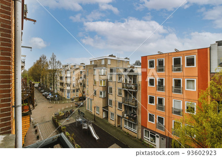 Panoramic view of old brick buildings with parking and trees from small balcony Panoramic view of old brick buildings with parking and trees from small balcony 93602923