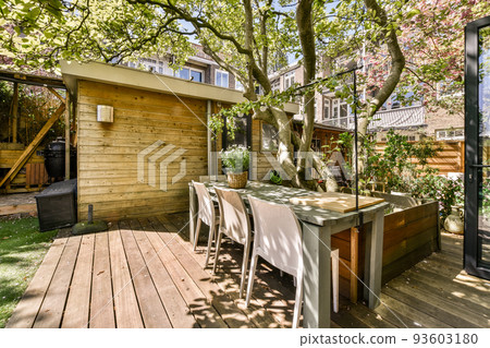 Neat paved patio with sitting area and small garden near wooden fence 93603180